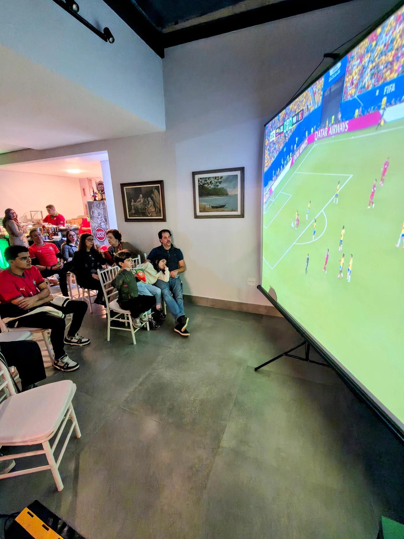 Famílias e convidados assistem ao jogo em uma grande projeção